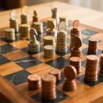 Game of chess being played with chess pieces made of Euro coins.